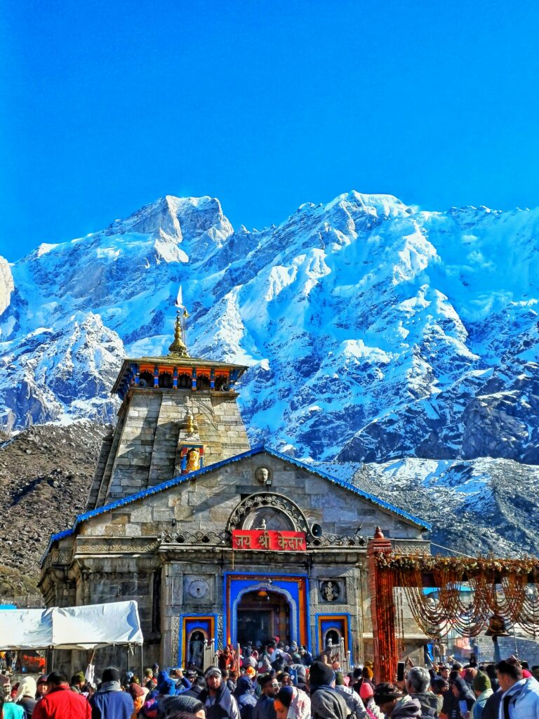Historic Kedarnath Temple amidst stunning snow-capped Himalayan peaks on a clear day.